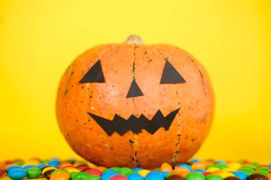 Komik yüz ve sarı arka plan üzerinde renkli şeker ile Halloween kabak jack o fener dekor. Mutlu Cadılar Bayramı kutlama konsepti. Hediye ver yoksa karışmam. Kopyalama alanı 