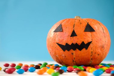 Komik yüz ve mavi arka plan üzerinde renkli şeker ile Halloween kabak jack o fener dekor. Hediye ver yoksa karışmam. Mutlu Cadılar Bayramı kutlama konsepti. Kopyalama alanı 