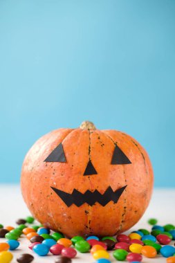 Komik yüz ve mavi arka plan üzerinde renkli şeker ile Halloween kabak jack o fener dekor. Hediye ver yoksa karışmam. Mutlu Cadılar Bayramı kutlama konsepti. Kopyalama alanı 