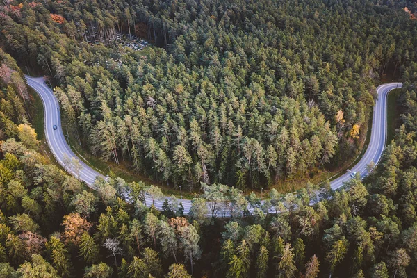 Aerial view of car driving through the forest on country road. Kaunas county, Lithuania
