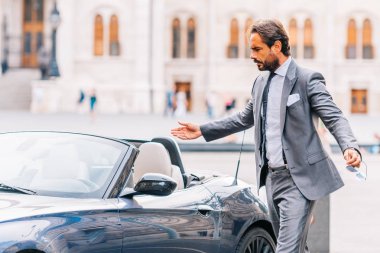 Takım elbise ayakta modern car yakınındaki emin iş adamı