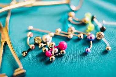 Vücut piercing takı halkaları, renkli arka plan üzerinde delinme implantlar