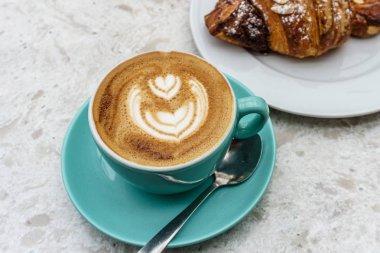 Masada köpük lü kahve ve kruvasan ile kahve üst görünümü.