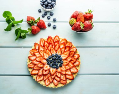 Çilek ile Kek Mavi rustik masada çilek ve yaban mersini ile Pasta.