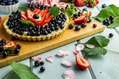 Çilek pasta ile kek çilek ve mavi rustik masada siyah kuş üzümü ile Pasta.