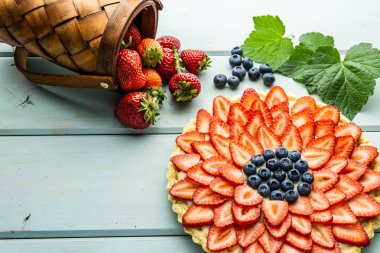 Çilek ile Kek Mavi rustik masada çilek ve yaban mersini ile Pasta.