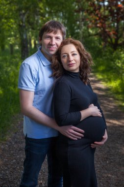 Kocasıyla yeşil parkta mutlu, güzel, hamile bir kadın.