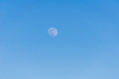 Küçük bir ay uzaklarda mavi gökyüzünde akşam vakti bir arka plan olarak.