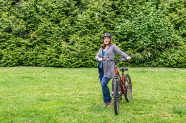 Parktaki yeşil çimenlikte hamile bir kadın bisiklete binmeye hazır..