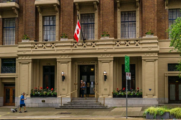 VANCOUVER, KANADA - 10. června 2020: lidé na ulici v deštivém dni poblíž historické budovy s kanadskou vlajkou — Stock fotografie