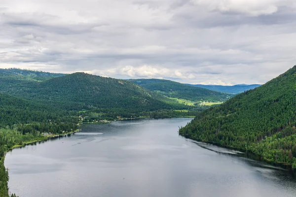 Tepeden Paul Gölü 'ne Yeşil dağlar ve beyaz bulutlar İngiliz Kolombiyası Kanada.