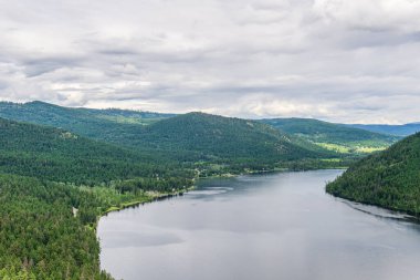 Tepeden Paul Gölü 'ne Yeşil dağlar ve beyaz bulutlar İngiliz Kolombiyası Kanada.