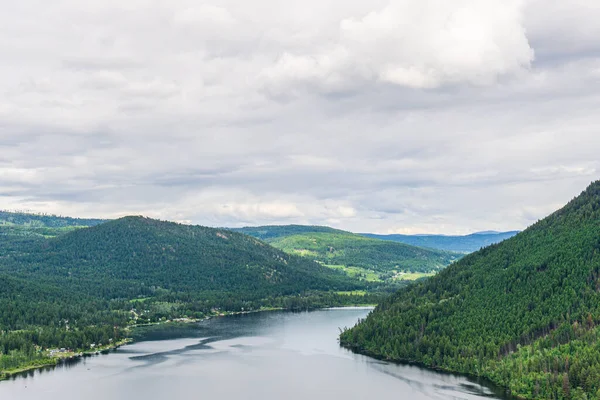 Tepeden Paul Gölü 'ne Yeşil dağlar ve beyaz bulutlar İngiliz Kolombiyası Kanada.