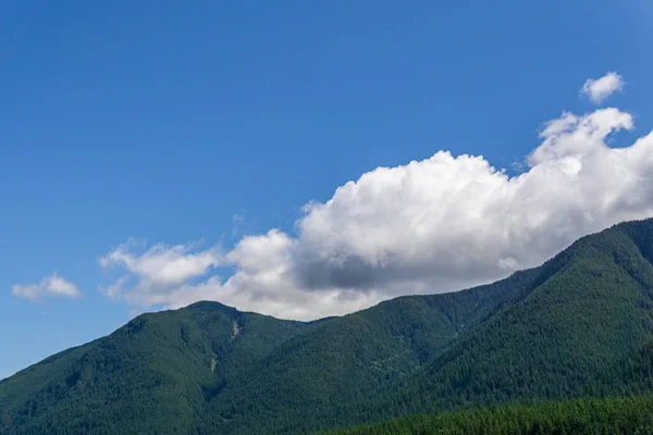 Montanhas cobertas de floresta verde céu azul com nuvens brancas — Fotografia de Stock