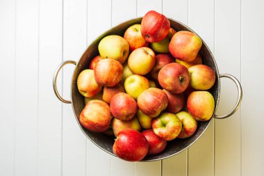 Olgun kırmızı elmalar ve karpuz çamaşır küvetinde beyaz ahşap arka plan görünümünde.