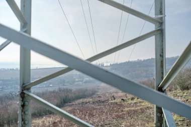 Dağ Vadisi 'ndeki elektrik iletim kulesinin metal çerçevesinden bakıyorum. Kesik ormanı kablolu yayın için kullanıyorum. Kırsal kesimde, güneşli bir günde yüksek voltajlı elektrik direkleri. Avrupa, Çek Cumhuriyeti. 