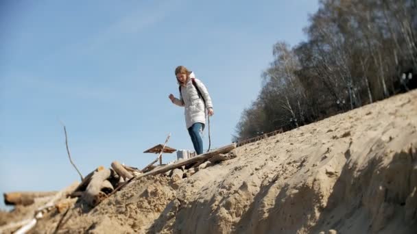 Mooie jonge vrouw lopen langs de rivieroever en het verzamelen van droge takken — Stockvideo