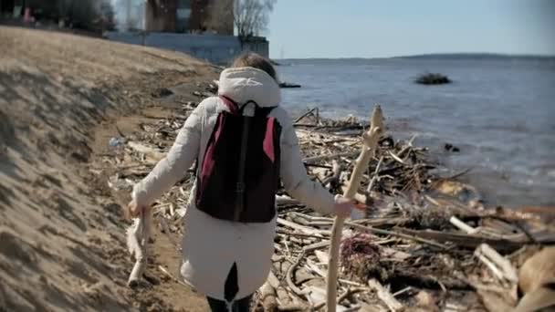 Bella giovane donna che cammina lungo la riva del fiume e raccogliendo rami secchi — Video Stock