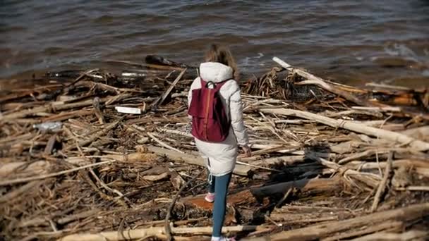 Vacker ung kvinna promenader längs flodstranden och samla torra grenar — Stockvideo