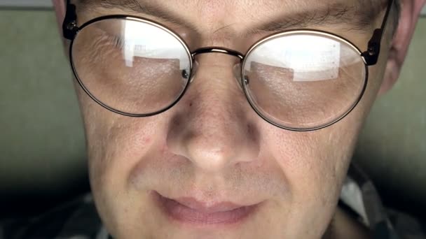 Ένας άνδρας με γυαλιά που λειτουργεί αργά τη νύχτα. Αυτός φαίνεται ανήσυχος, βλέπει στην οθόνη του υπολογιστή μπροστά του, μια στενή-up — Αρχείο Βίντεο