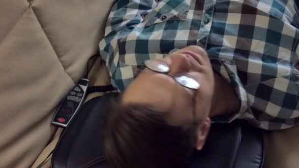 Man lies on the couch at home, under the head of a massager, relaxed state — Stock Video