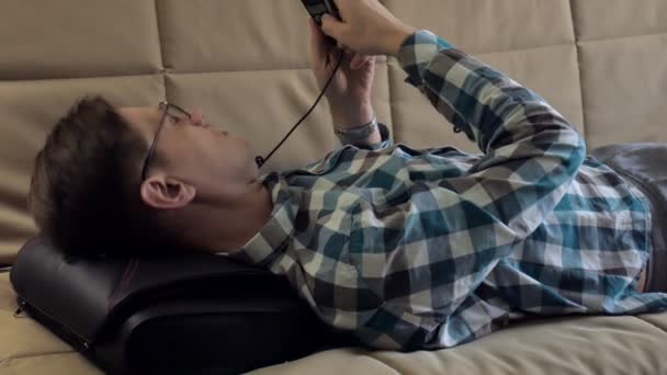 Man lies on the couch at home, under the head of a massager, relaxed state — Stock Video