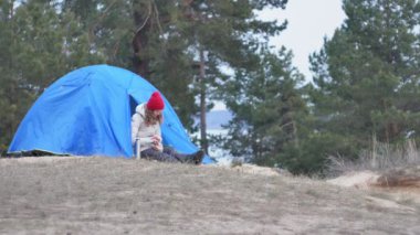 Kırmızı bir şapka çekici genç kadın turist turist çadırda oturur ve bir termos çay içer