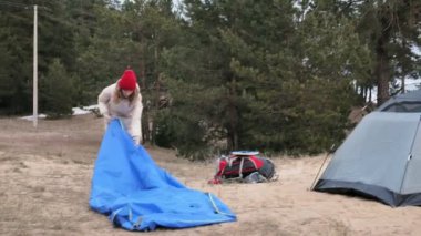 Çekici genç turist kadın kırmızı şapkalı bir turist çadır forest yakınındaki sahil üzerinde toplar.