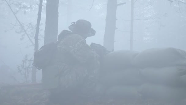 Солдати в камуфляжі з бойовою зброєю стріляють у лісовий притулок, військова концепція, димовий екран, туман — стокове відео