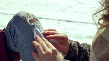 Genç bir kadın sessizce origami kağıt uçak parmakları ile dokunarak ve dizlerinin üzerinde koyarak bir ahşap verandada oturuyor. Açık havada beyaz aerogamy uçak ile oturan kız yakın görünümü,