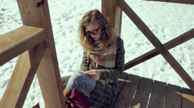 Genç bir kadın sessizce origami kağıt uçak parmakları ile dokunarak ve dizlerinin üzerinde koyarak bir ahşap verandada oturuyor. Açık havada beyaz aerogamy uçak ile oturan kız yakın görünümü,