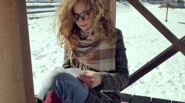 Genç bir kadın sessizce origami kağıt uçak parmakları ile dokunarak ve dizlerinin üzerinde koyarak bir ahşap verandada oturuyor. Açık havada beyaz aerogamy uçak ile oturan kız yakın görünümü,