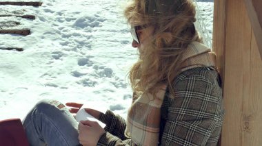 Genç bir kadın sessizce origami kağıt uçak parmakları ile dokunarak ve dizlerinin üzerinde koyarak bir ahşap verandada oturuyor. Açık havada beyaz aerogamy uçak ile oturan kız yakın görünümü,