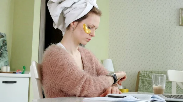 Aantrekkelijke zakenvrouw cosmetische gezichts plekken thuis, toe te passen op die zijn werken achter een laptop — Stockfoto