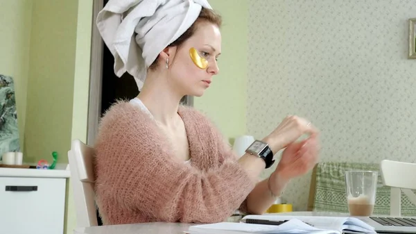 Aantrekkelijke zakenvrouw cosmetische gezichts plekken thuis, toe te passen op die zijn werken achter een laptop — Stockfoto