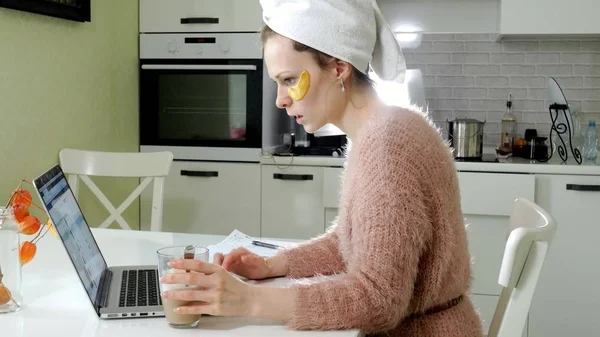 Attraktiva affärskvinna tillämpa kosmetiska ansikts ställen hemma, arbetar bakom laptop — Stockfoto