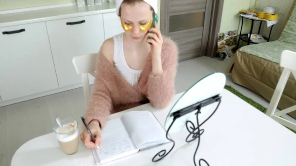 Mulher de negócios atraente aplicando manchas faciais cosméticos em casa, falando ao telefone — Fotografia de Stock