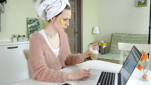 Aantrekkelijke zakenvrouw cosmetische gezichts plekken thuis, toe te passen op die zijn werken achter een laptop — Stockfoto