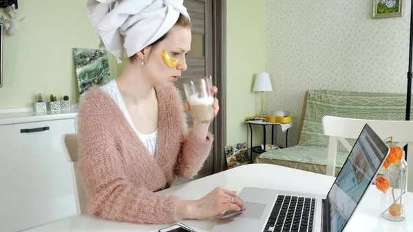 Aantrekkelijke zakenvrouw cosmetische gezichts plekken thuis, toe te passen op die zijn werken achter een laptop — Stockfoto