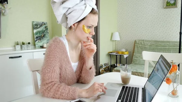 Attraente donna d'affari che applica macchie facciali cosmetici a casa, lavorando dietro il computer portatile — Foto Stock