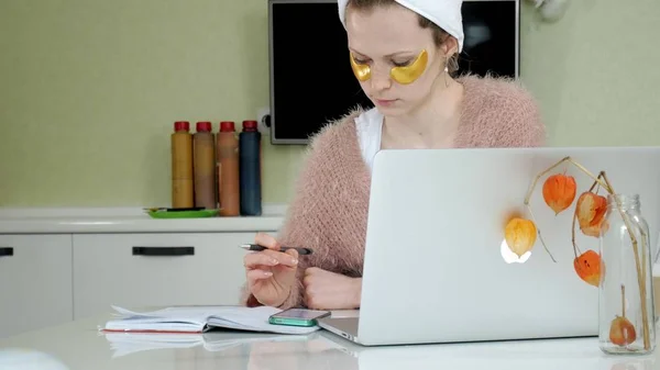 Mulher de negócios atraente aplicando manchas faciais cosméticos em casa, trabalhando atrás do laptop — Fotografia de Stock