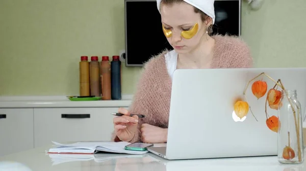 Aantrekkelijke zakenvrouw cosmetische gezichts plekken thuis, toe te passen op die zijn werken achter een laptop — Stockfoto