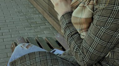 Genç kadın bir bahar parkta bir bankta oturan bir termos şişe çay içme