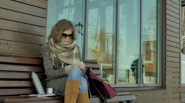 Genç kadın ve erkek bir bahar parkta bir bankta oturan bir termos şişe çay içme