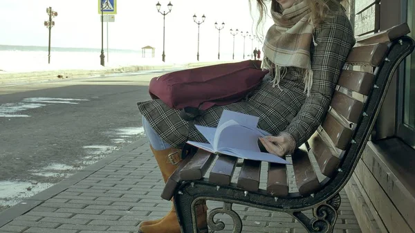 年轻, 美丽, 可爱的女人坐在公园的长凳上, 在她的笔记本手。她穿着一件大衣。她做笔记, 看起来很浪漫. — 图库照片