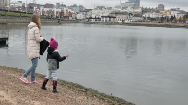 Happy and beautiful mother and daughter are feeding gulls on the beach on the river bank — Stock Video