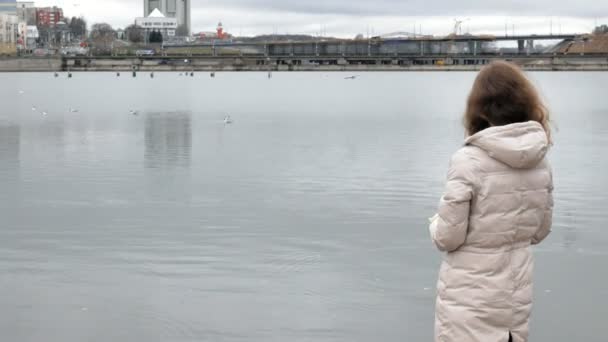Mãe e filha felizes e bonitas estão alimentando gaivotas na praia na margem do rio — Vídeo de Stock