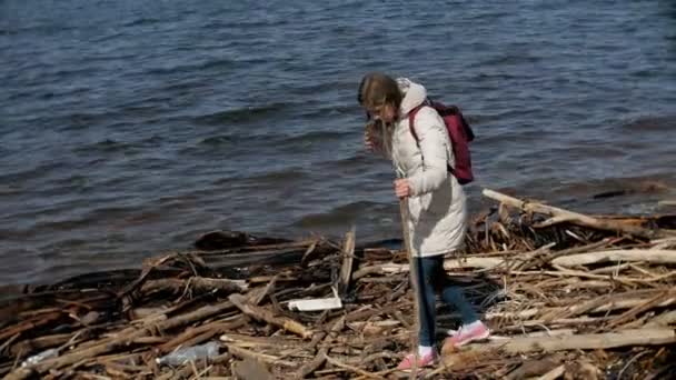 Bella giovane donna che cammina lungo la riva del fiume e raccogliendo rami secchi — Video Stock