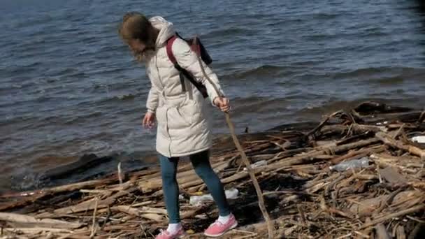 Vacker ung kvinna promenader längs flodstranden och samla torra grenar — Stockvideo