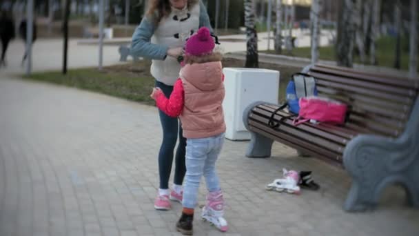 Maman et fille roulent en patins à roulettes. Une fille apprend à patiner et tombe. Maman enseigne fille à monter sur des rouleaux — Video